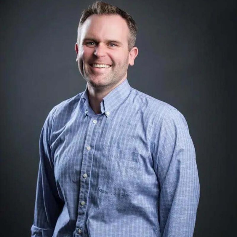 Smiling man in blue shirt against gray background