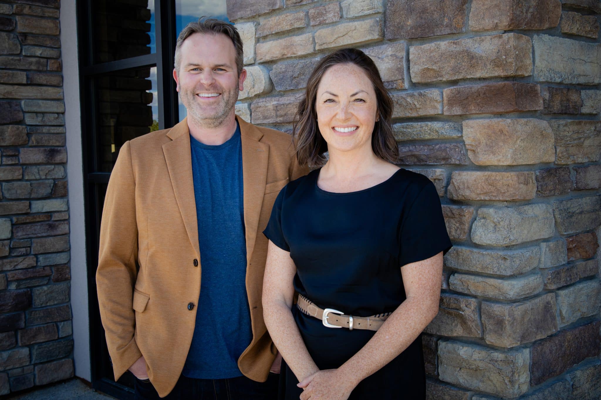 Man and woman smiling outside stone building